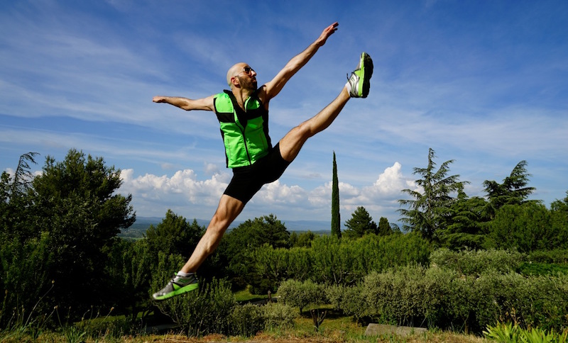 Daniel pikes his legs in front of him making a parallel line with the ground. He supports himself by a metal railing.
